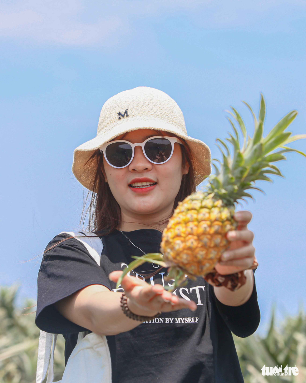 A young woman poses for a photo with a pineapple at the 170-hectare pineapple hill in Bao Son Ward, Luc Nam District, Bac Giang Province. Photo: Ha Quan / Tuoi Tre