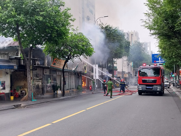 Firefighters spray water on a fire at a painting shop in District 1, Ho Chi Minh City, July 1, 2022. Photo: Minh Hoa / Tuoi Tre
