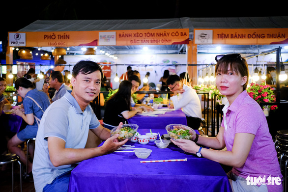 Two visitors enjoy 'bun hen Hue' (Hue baby mussel noodles) at the Da Nang food festival at Bien Dong Park, Da Nang, Vietnam on July 3, 2022. Photo: Tan Luc / Tuoi Tre