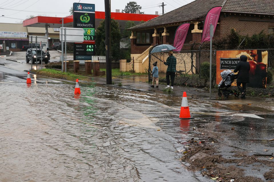 People walk past floodwaters following heavy rains in the Windsor suburb of Sydney, Australia, July 5, 2022. Photo: Reuters