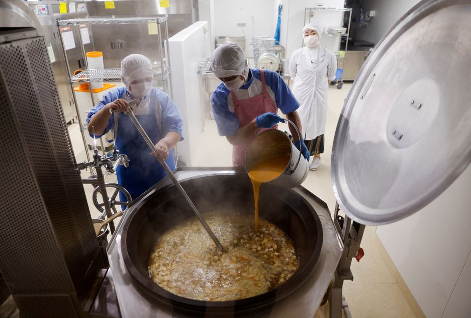 Cooks prepare for a school lunch as nutritionist Kazumi Sato looks on, inside the cookroom at Senju Aoba Junior High School in Tokyo, Japan, June 29, 2022. Photo: Reuters