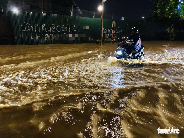 A resident rides a motorbike on a flooded street in Hanoi, July 5, 2022. Photo: Q. The / Tuoi Tre