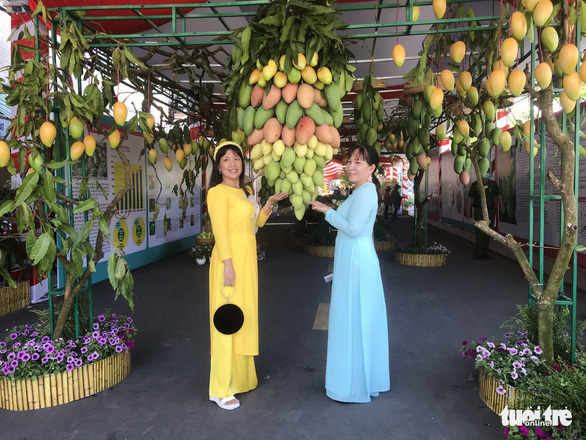 Two women pose for a photo in the Vietnamese traditional dress at ‘Le hoi xoai Cao Lanh 2022’ (Cao Lanh mango festival 2022) in Cao Lanh City, Dong Thap Province, Vietnam. Photo: Dang Tuyet / Tuoi Tre