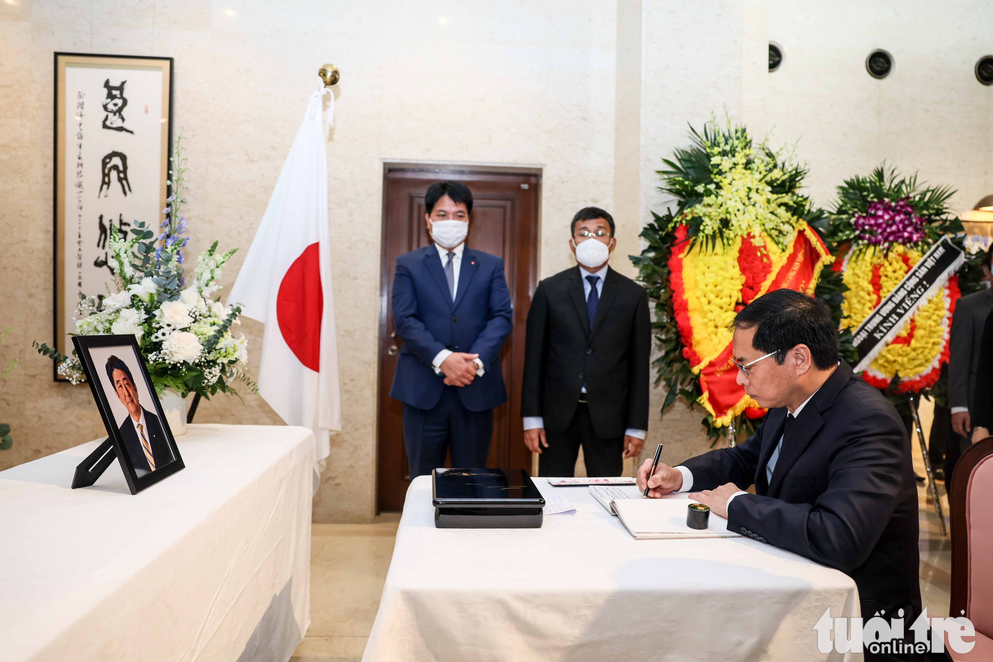 Vietnamese Minister of Foreign Affairs Bui Thanh Son writes on the condolence book for former Japanese Prime Minister Shinzo Abe at the Embassy of Japan in Hanoi, July 11, 2022. Photo: Nguyen Khanh / Tuoi Tre