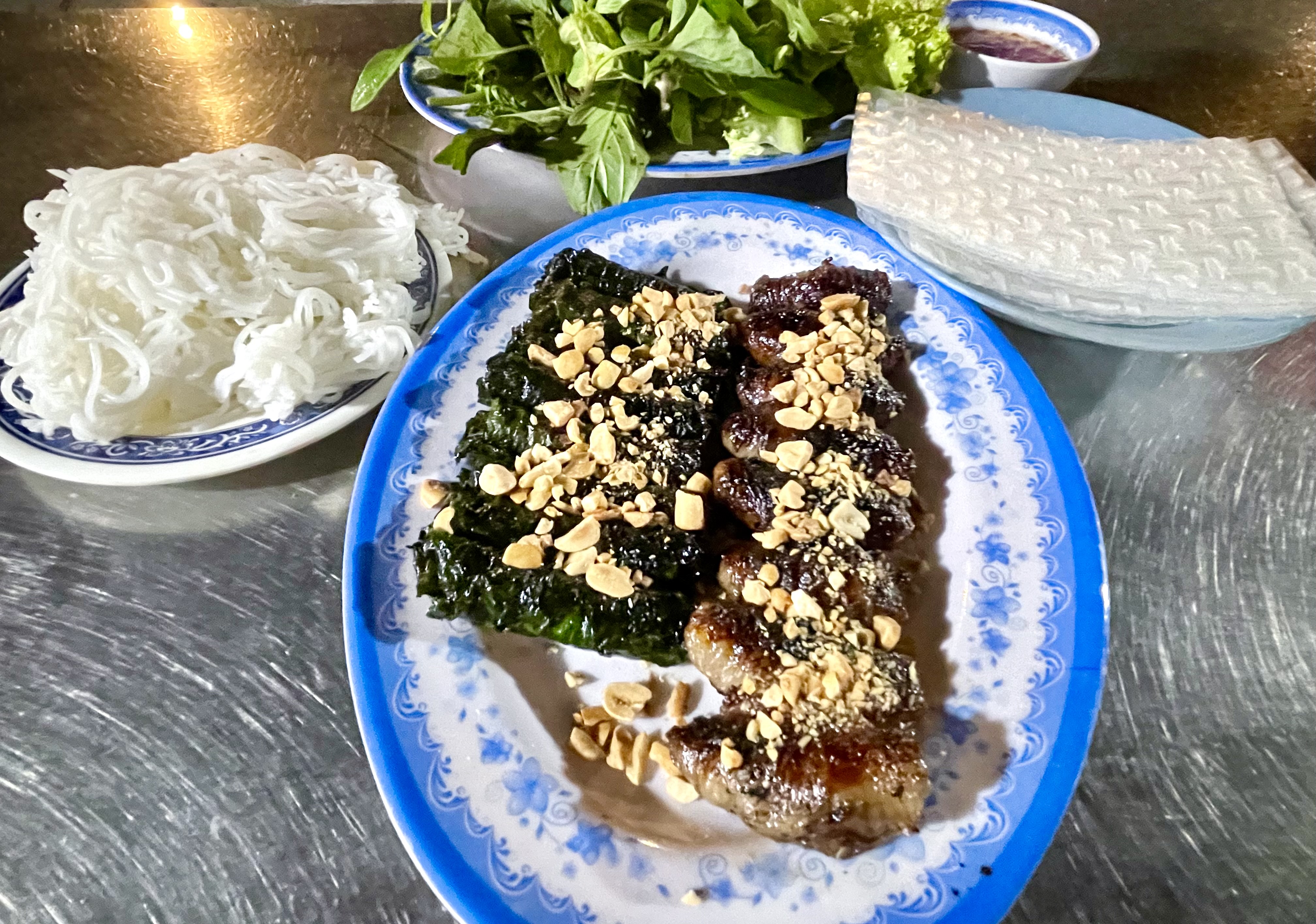 Two types of Vietnamese grilled beef rolls called 'bò nướng lá lốt' and 'bò nướng mỡ chài' are served with noodles, rice paper, and vegetables. Photo: Jordy Comes Alive