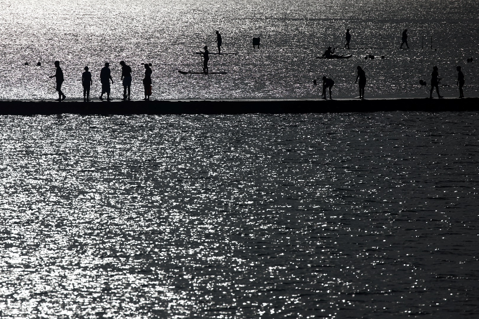 People walk on the ledge of a bathing pool in the sea in Margate, Britain, July 17, 2022. Photo: Reuters