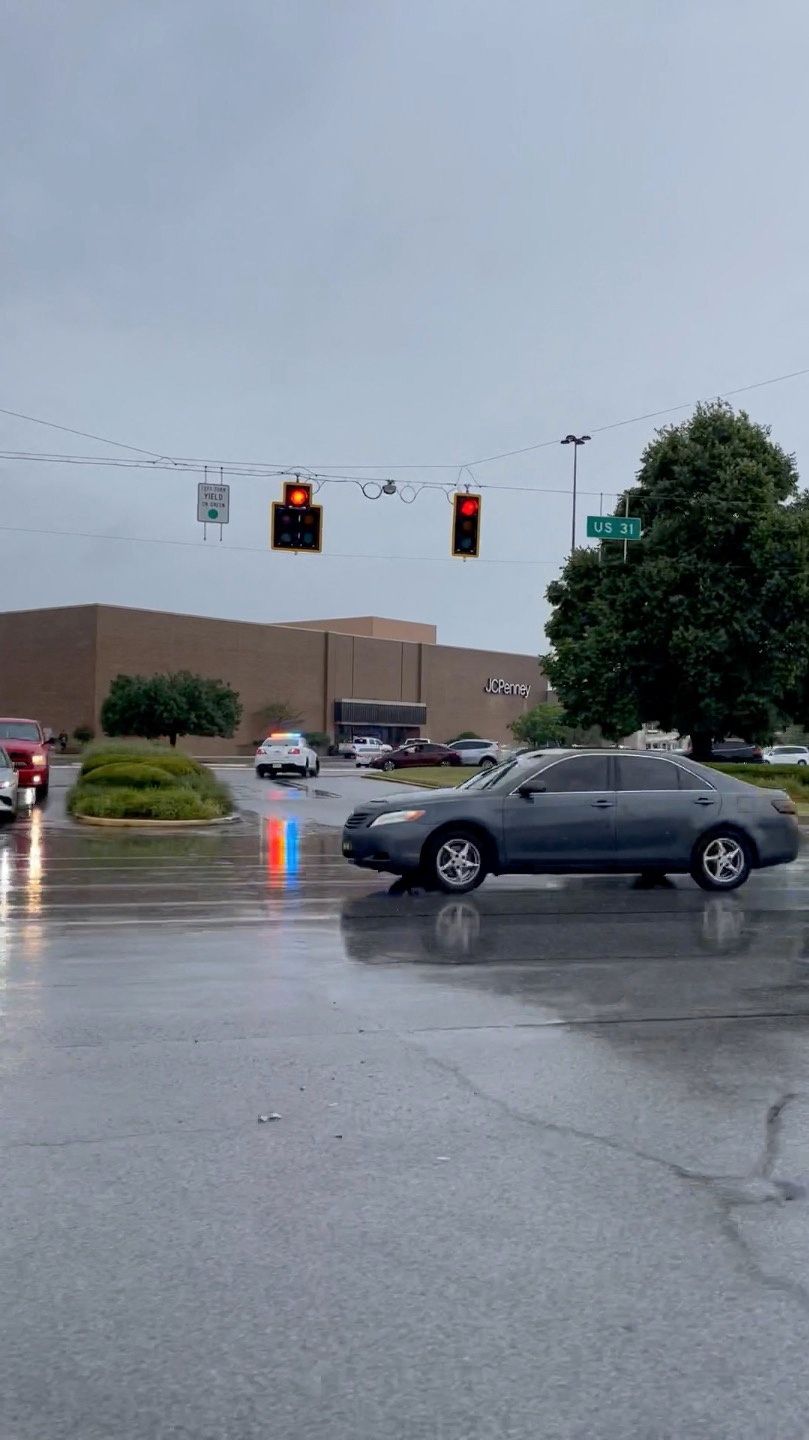 A car drives past police presence outside the Greenwood Park Mall after reports of shots fired, in Greenwood, Indiana, U.S. July 17, 2022 in this screen grab obtained from social media video. Francisco Jimenez/via Reuters