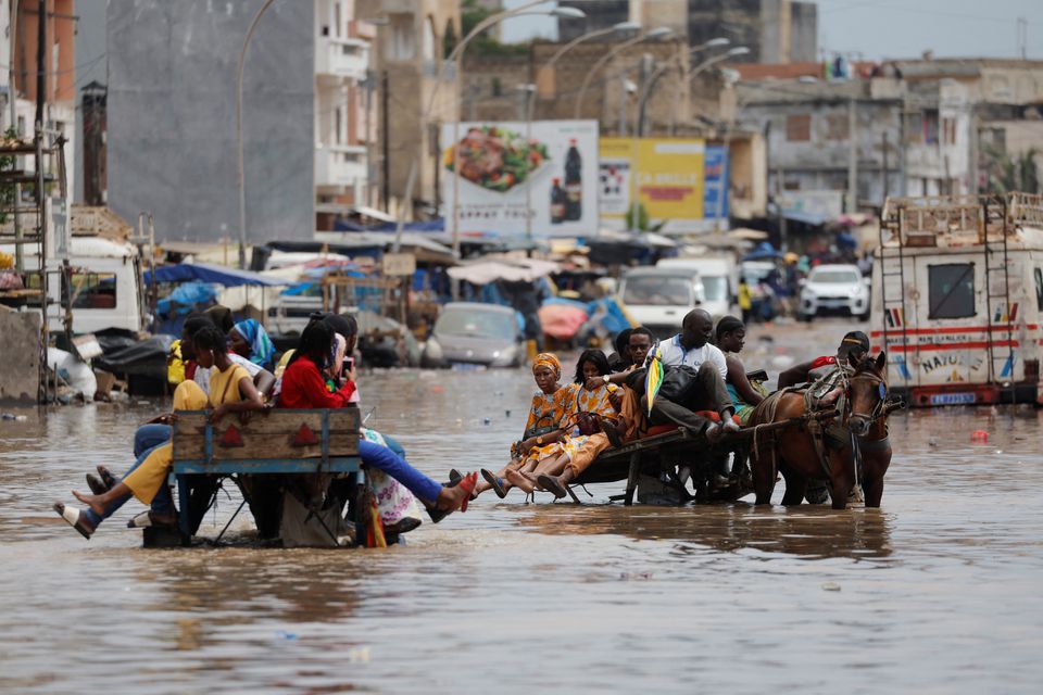 Residents make their way through a flooded street after heavy rains in Yoff, district of Dakar, Senegal July 20, 2022. Photo: Reuters