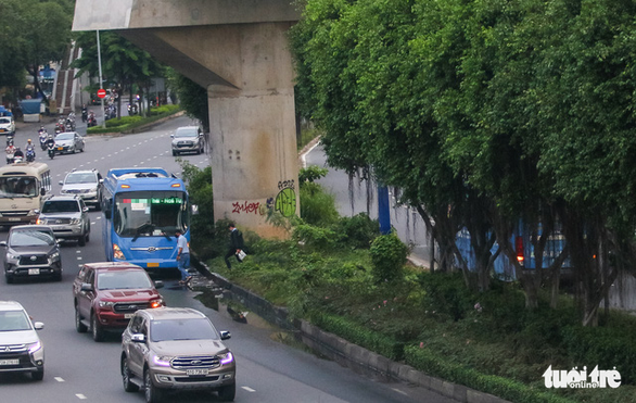 This image shows two buses, one of which is obscured by the trees, blatantly stopping next to the median strip for a chat between the drivers. Photo: Chau Tuan / Tuoi Tre