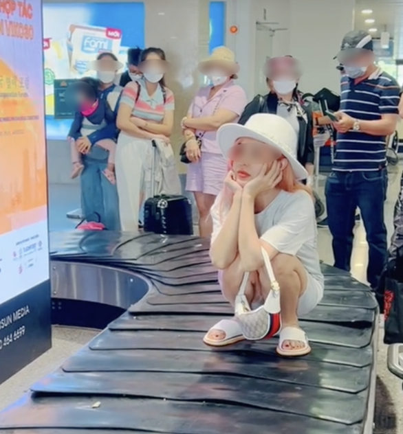 This screenshot from a TikTok video shows a woman posing for social media content while sitting on the conveyer belt at Tan San Nhat International Airport, Ho Chi Minh City, Vietnam.