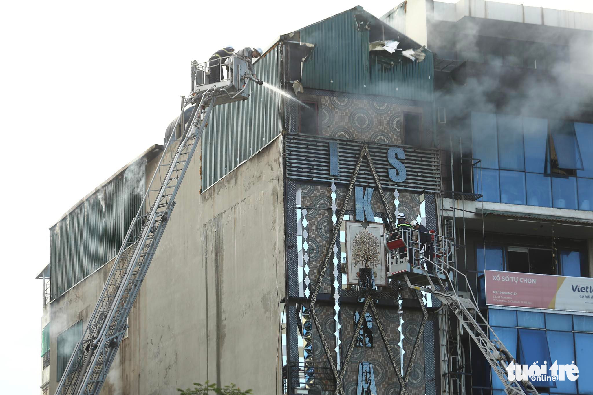 Firefighters use two fire ladders to approach a blaze that broke out on the fifth floor of a karaoke parlor in Cau Giay District, Hanoi, August 1, 2022. Photo: Nam Tran / Tuoi Tre