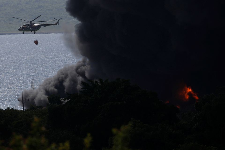 A helicopter throws water over fuel storage tanks that exploded near Cuba's supertanker port in Matanzas, Cuba, August 6, 2022. Photo: Reuters