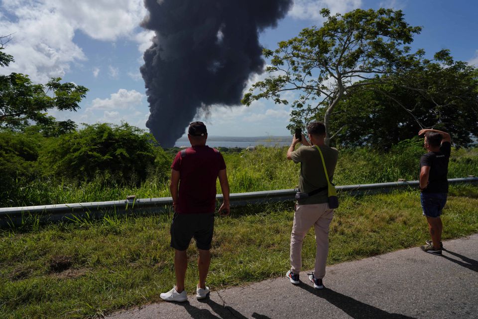 People take pictures of a fire over fuel storage tanks that exploded near Cuba's supertanker port in Matanzas, Cuba, August 6, 2022. Photo: Reuters