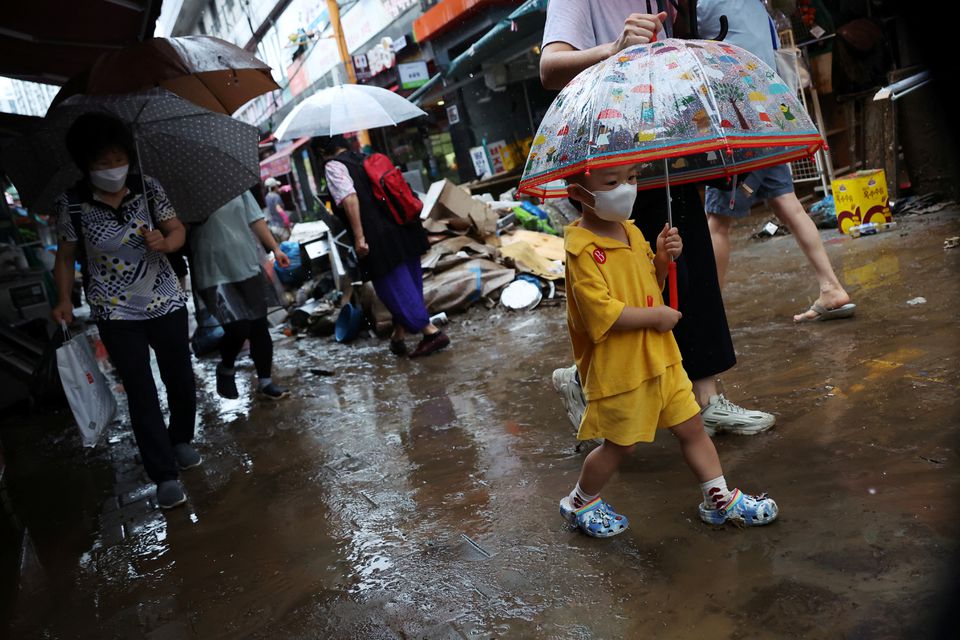 A boy using an umbrella makes his way through a road that was flooded after torrential rain at a traditional market in Seoul, South Korea, August 9, 2022. Photo: Reuters