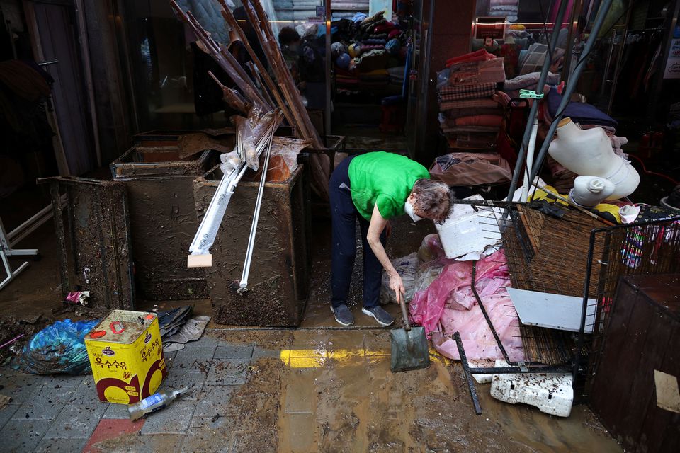 A woman cleans up debris at a blanket shop damaged by flood after torrential rain at a traditional market in Seoul, South Korea, August 9, 2022. Photo: Reuters