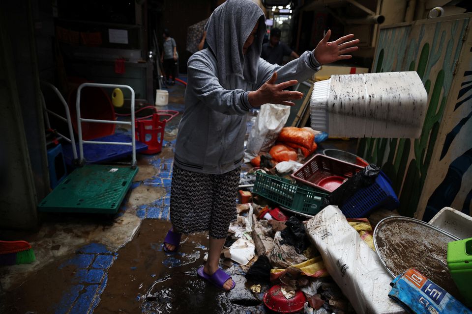 Kim Sun-ok cleans up debris from her restaurant damaged by flood after torrential rain at a traditional market in Seoul, South Korea, August 9, 2022. Photo: Reuters