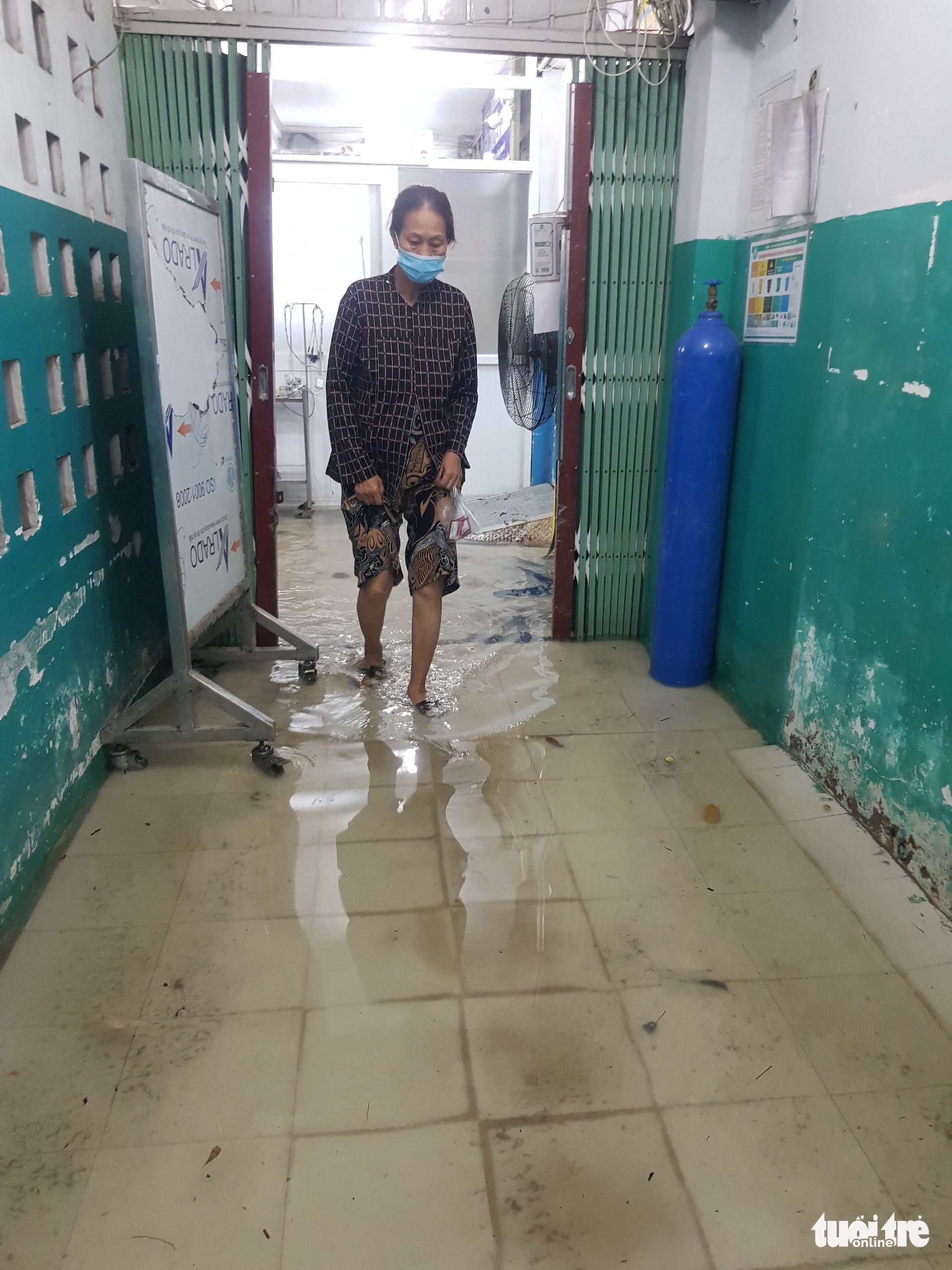 A patient’s relative wades through rainwater at Hoc Mon General Hospital in Hoc Mon District, Ho Chi Minh City, August 15, 2022. Photo: Ngoc Khai / Tuoi Tre