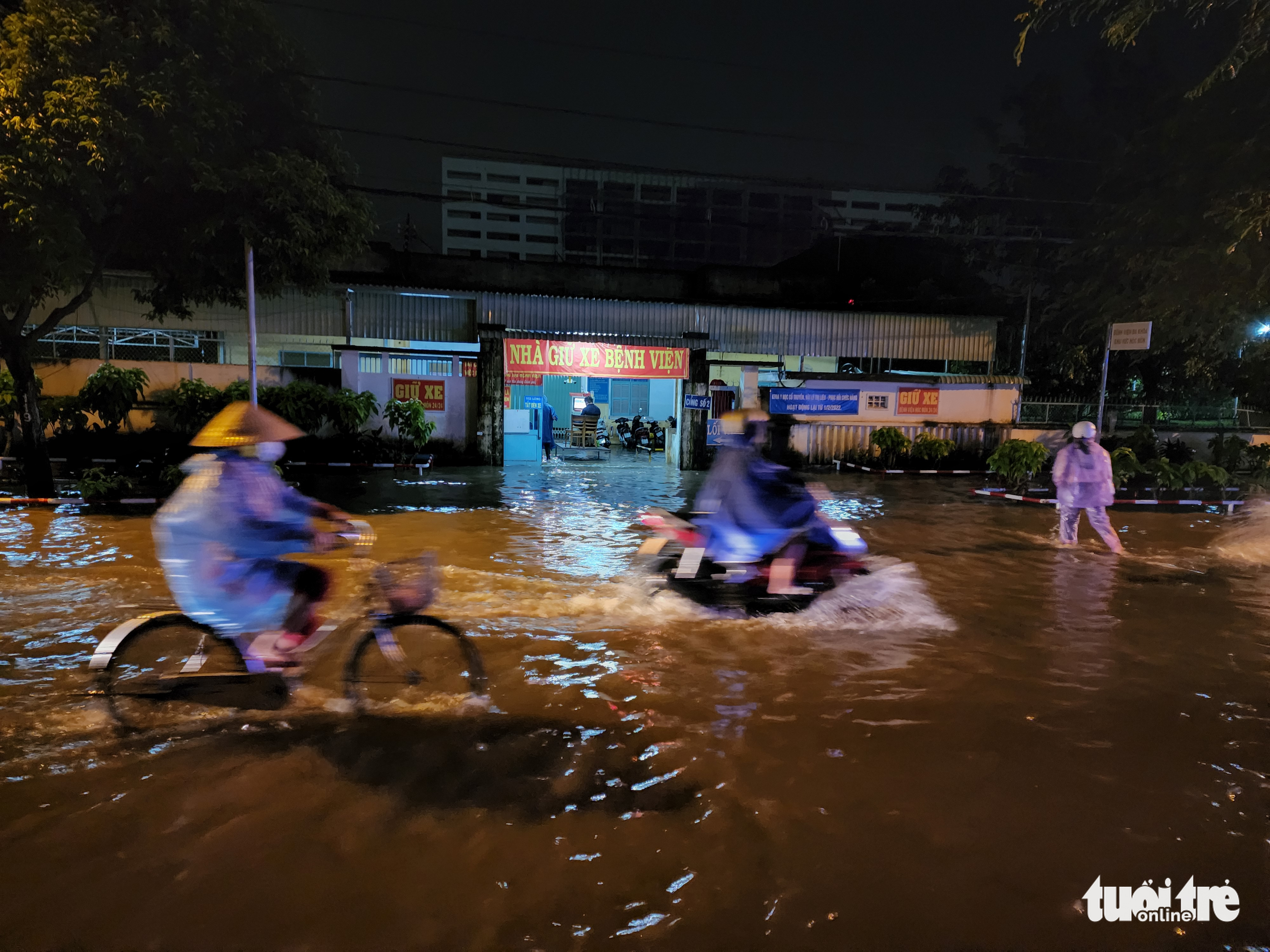 Vehicles drive through rainwater past the parking lot of Hoc Mon General Hospital in Hoc Mon District, Ho Chi Minh City, August 15, 2022. Photo: Ngoc Khai / Tuoi Tre