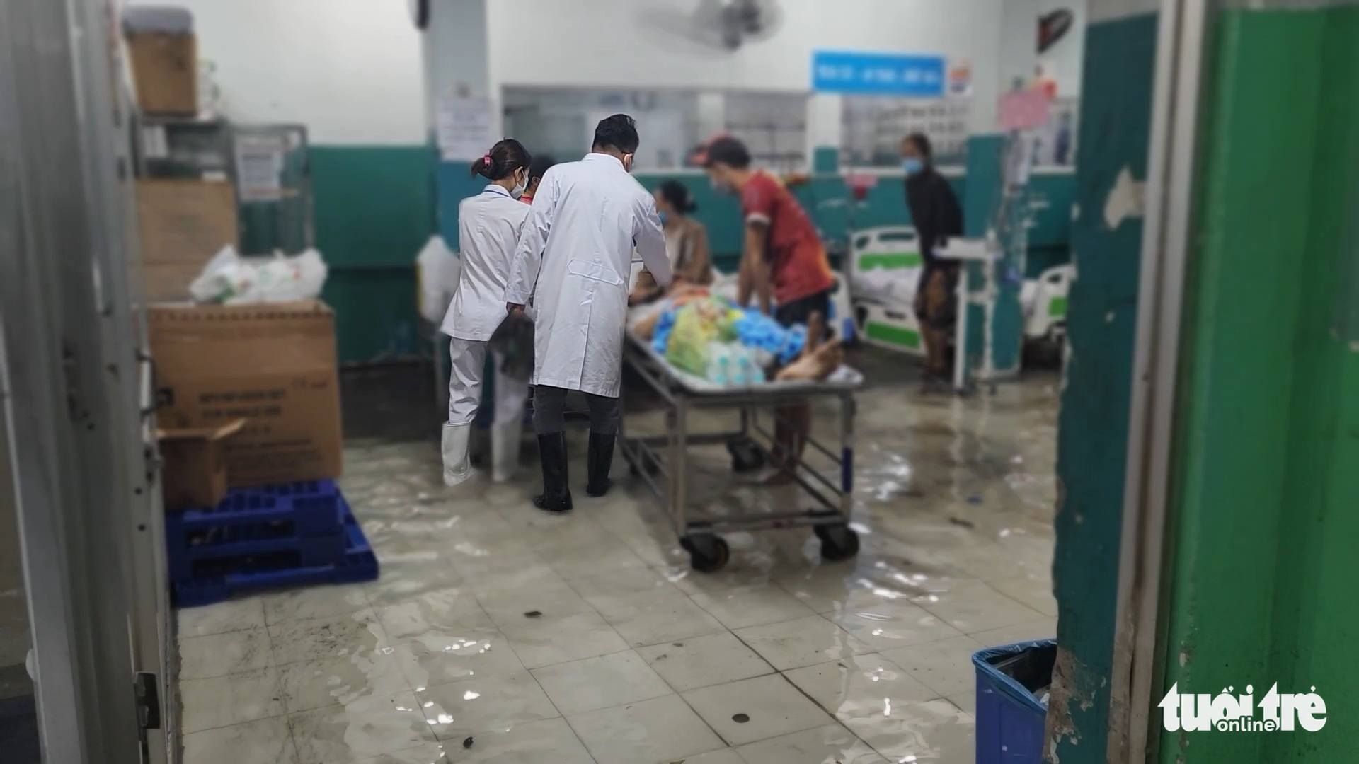 A doctor and a nurse wearing rubber boots give treatment to a patient at the inundated emergency department of Hoc Mon General Hospital in Hoc Mon District, Ho Chi Minh City, August 15, 2022. Photo: Ngoc Khai / Tuoi Tre