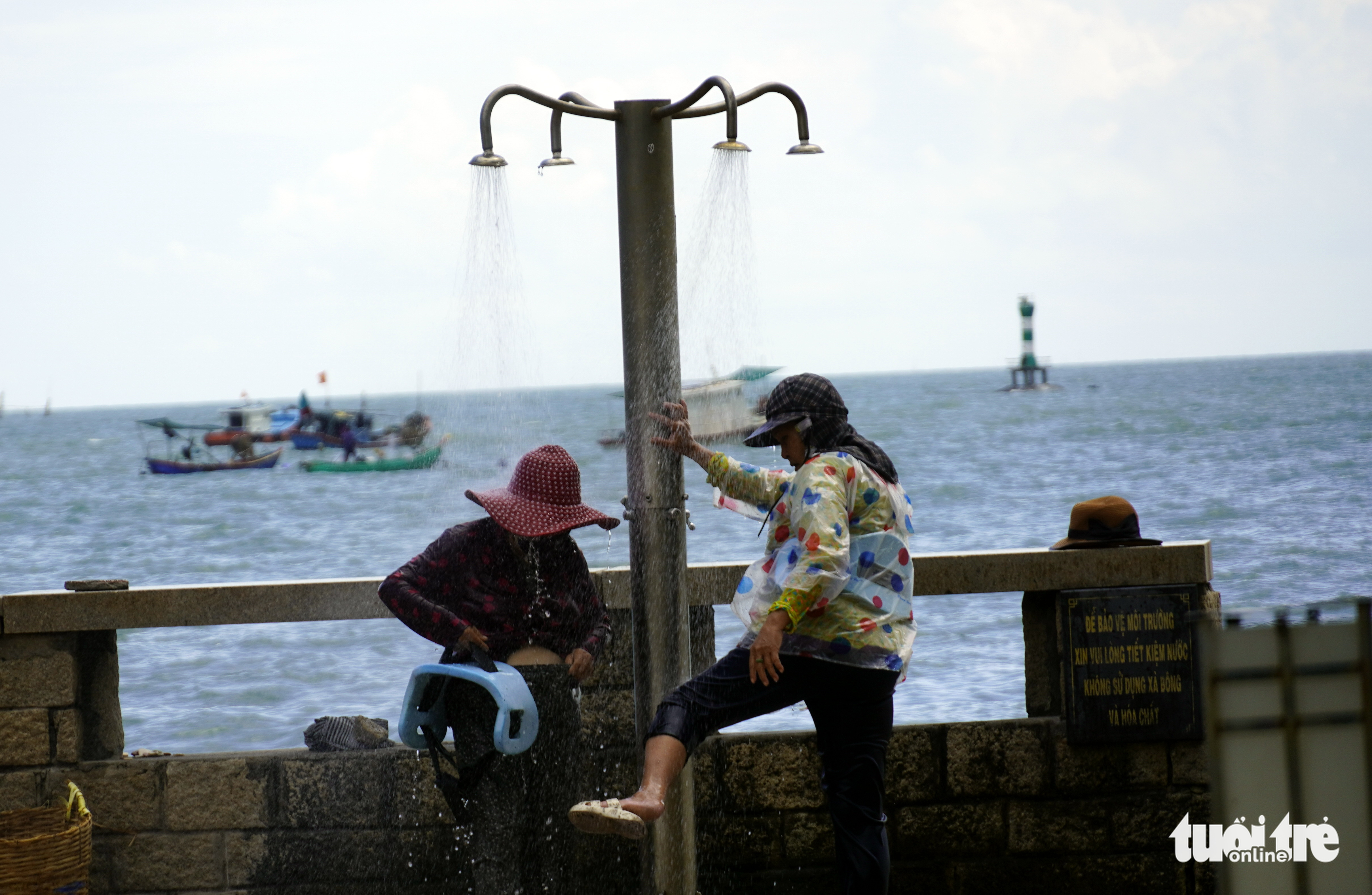 Two women wash without shampoo next to a sign warning people against using soap at a public beach shower in Vung Tau City, Ba Ria-Vung Tau Province, August 16, 2022. Photo: Dong Ha / Tuoi Tre