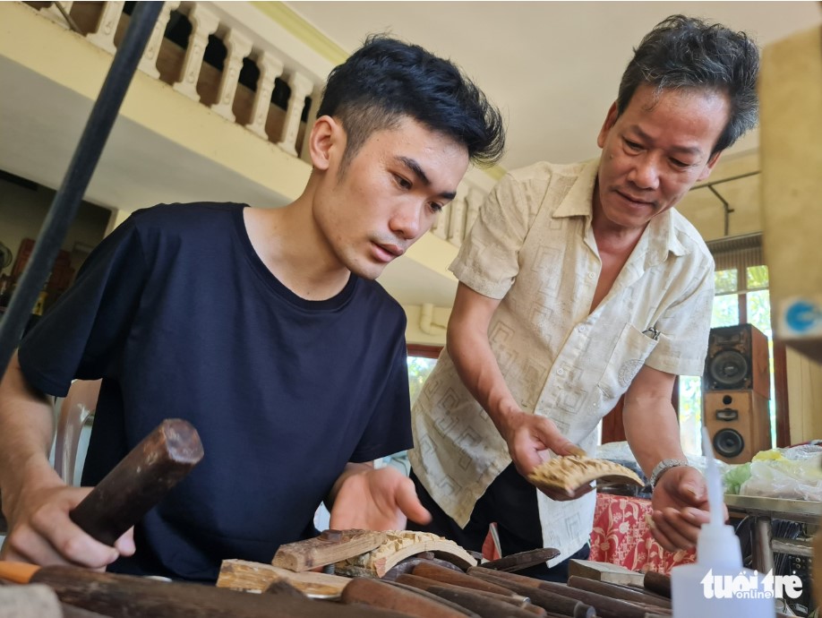 Artisan Doan Minh Can (right) teaches a young apprentice how to carve a bamboo birdcage. Photo: T. Mai / Tuoi Tre