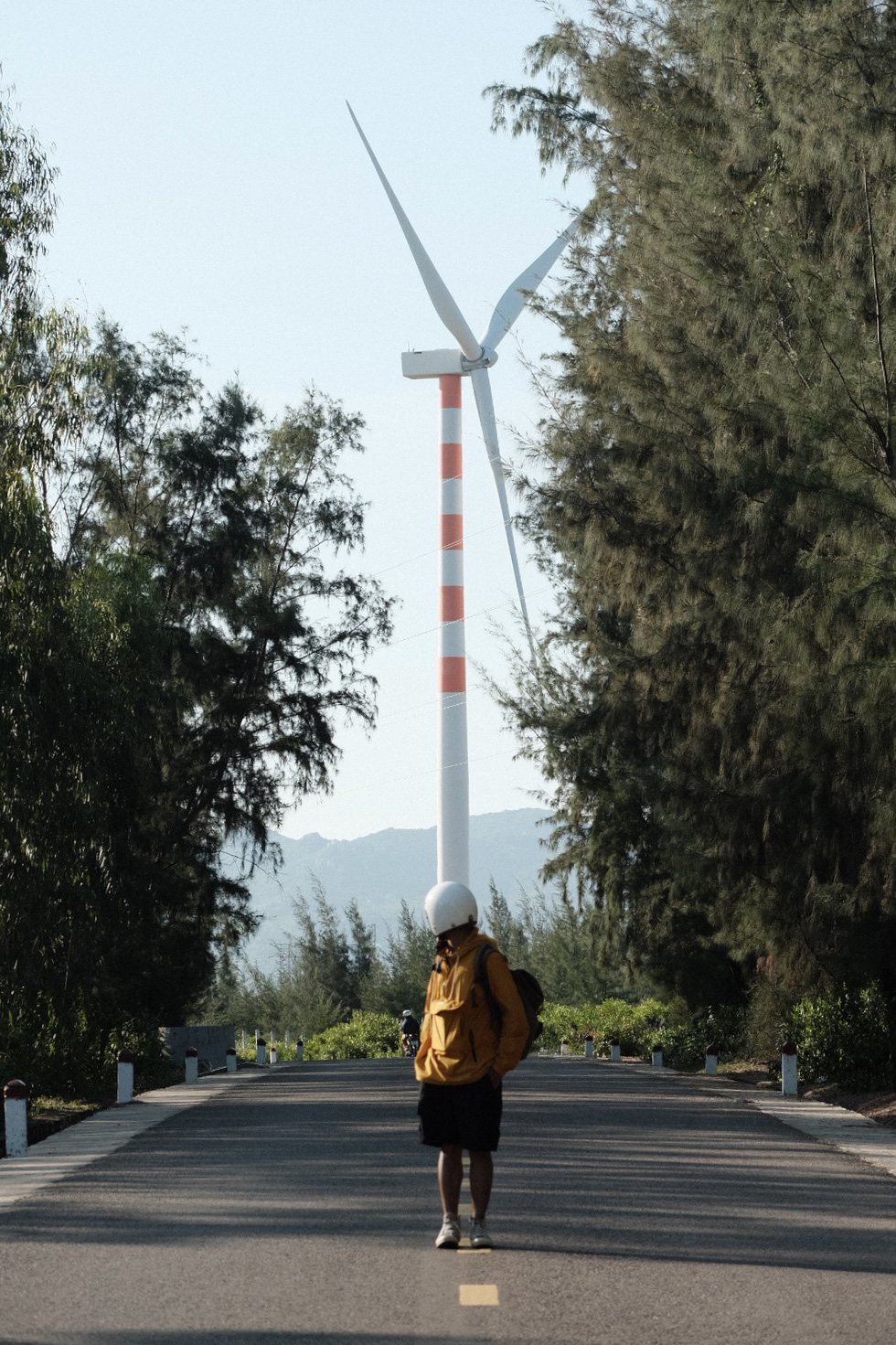 A tourist poses for a photo against a background of wind turbines in Quy Nhon City, Binh Dinh Province, south-central Vietnam. Photo: Lo Huu Duc Anh / Tuoi Tre