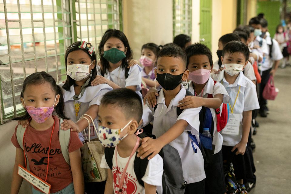 Students wearing masks for protection against the coronavirus disease (COVID-19) prepare to enter their classrooms on the first day of in-person classes at a public school in San Juan City, Philippines, August 22, 2022. Photo: Reuters