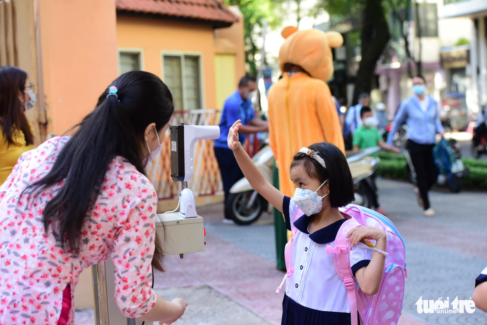 An elementary student washes her hands and has her body temperature measured before entering a school in Ho Chi Minh City, August 22, 2022. Photo: Duyen Phan / Tuoi Tre
