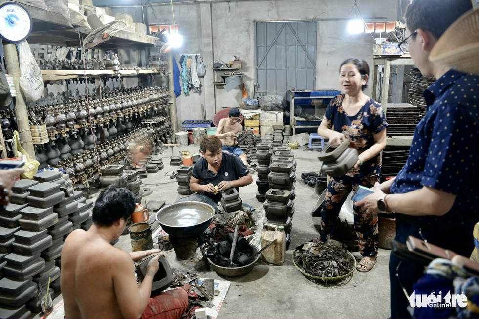 Pham Thi Lien, owner of the Ba Co bronze casting facility in Ward 12, Go Vap District, Ho Chi Minh City, teaches visitors how to make a bronze burner. Photo: T.T.D / Tuoi Tre