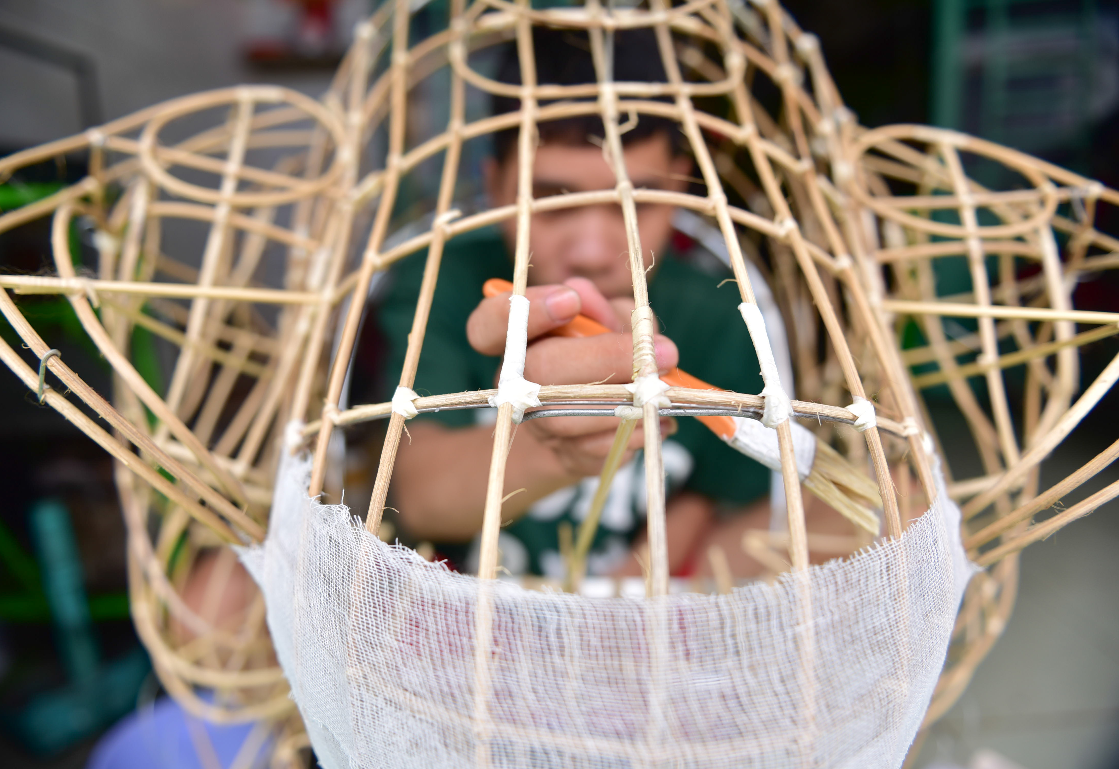 A craftsman glues pieces of fabric and paper onto a lion head frame. Photo: Ngoc Phuong / Tuoi Tre News