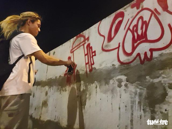 A graffiti artist paints a bus stop on Nguyen Huu Canh Street. Photo: Hoang Loc / Tuoi Tre