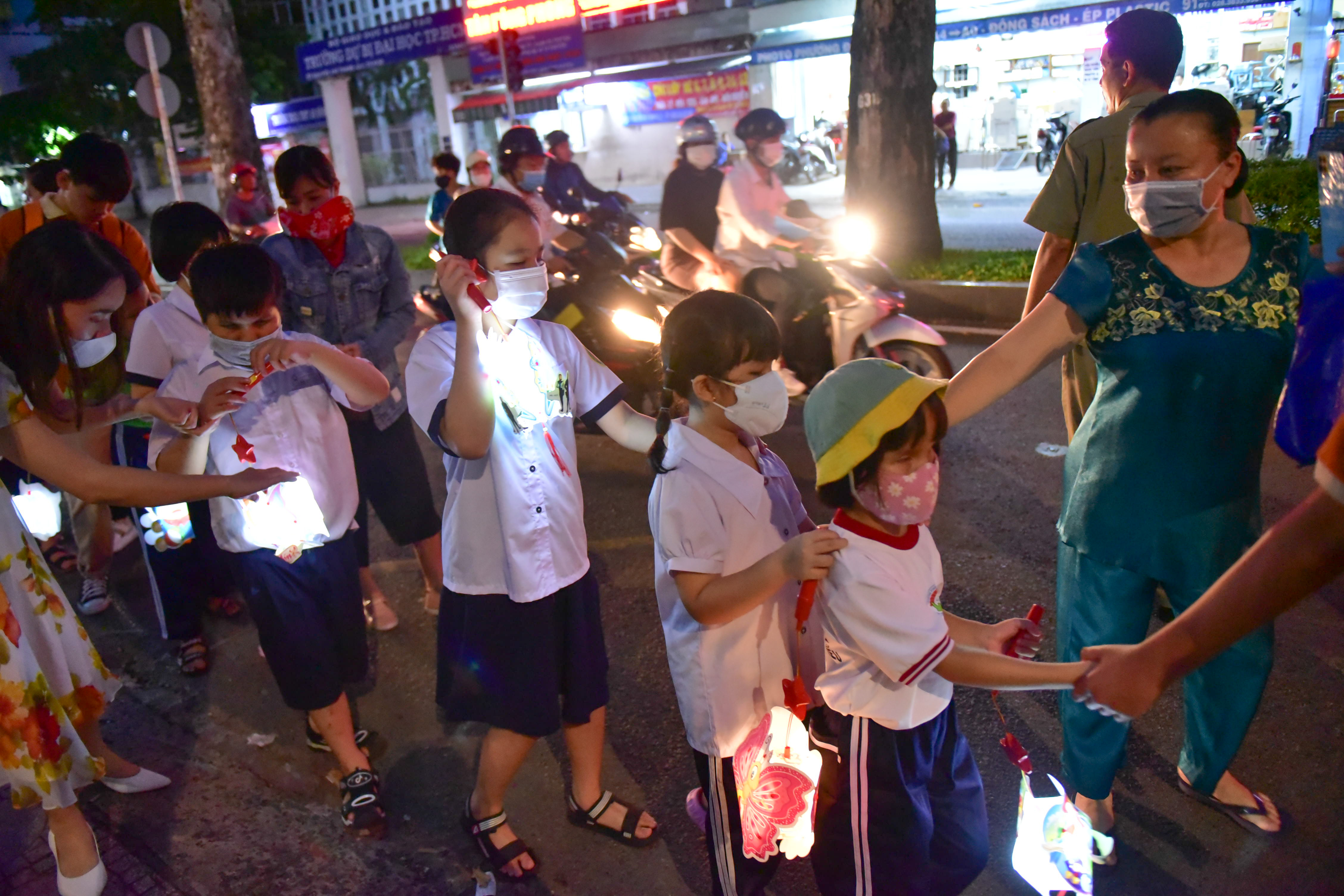 Children assisted by adults while participating in a lantern parade to celebrate the Mid-Autumn Festival held by Nguyen Dinh Chieu Special School for the Blind in District 10, Ho Chi Minh City on September 9, 2022. Photo: Ngoc Phuong / Tuoi Tre News