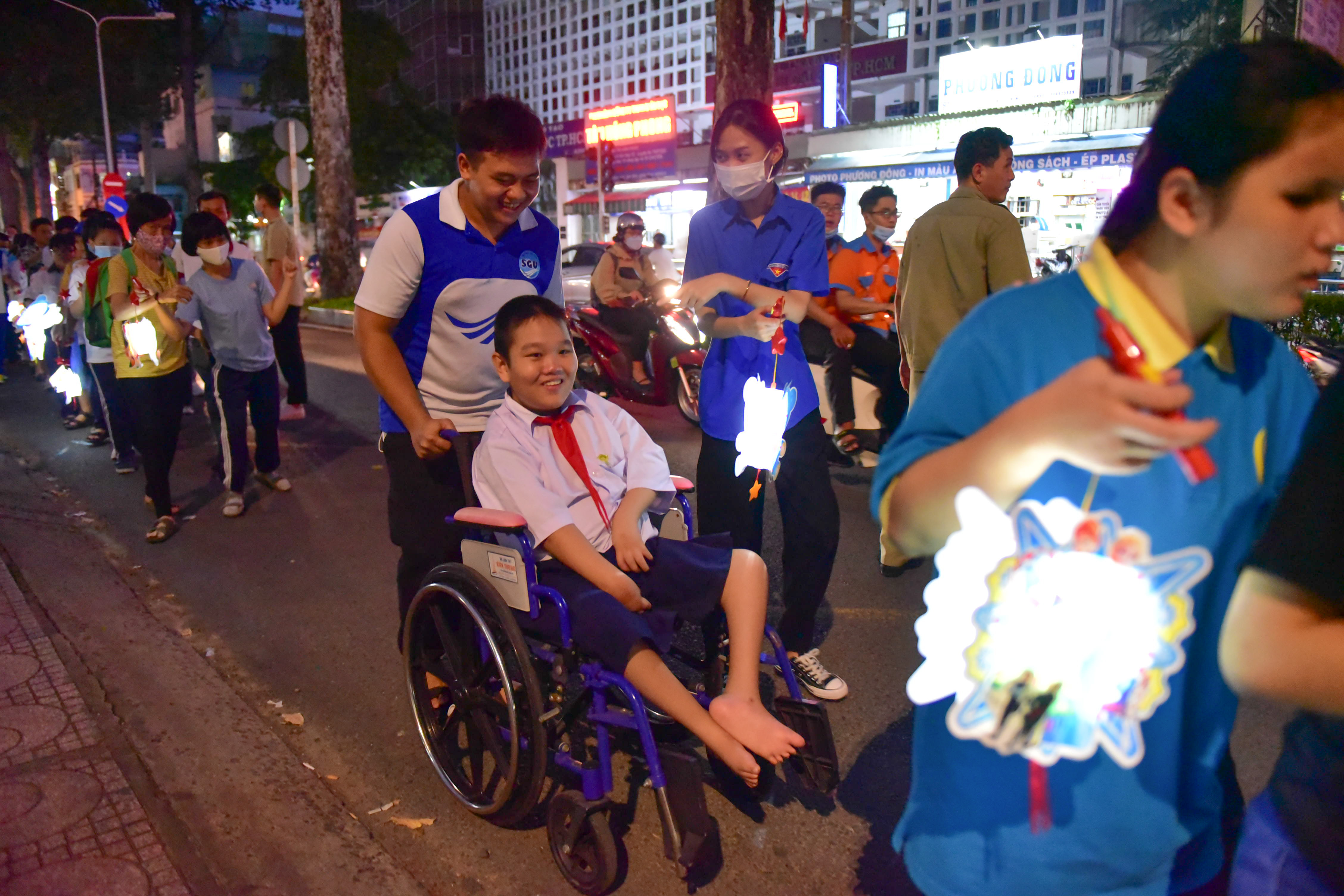 Fifth grader Lau Gia Tue is assisted to attend on wheelchair a lantern parade to celebrate the Mid-Autumn Festival held by Nguyen Dinh Chieu Special School for the Blind in District 10, Ho Chi Minh City on September 9, 2022. Photo: Ngoc Phuong / Tuoi Tre News