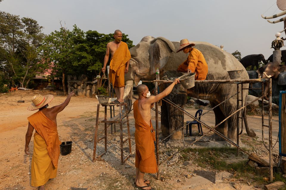 Buddhist monks work on an elephant sculpture at a temple in front of the elephant cemetery at Ba Ta Klang elephant village in Surin, Thailand April 7, 2022. Photo: Reuters