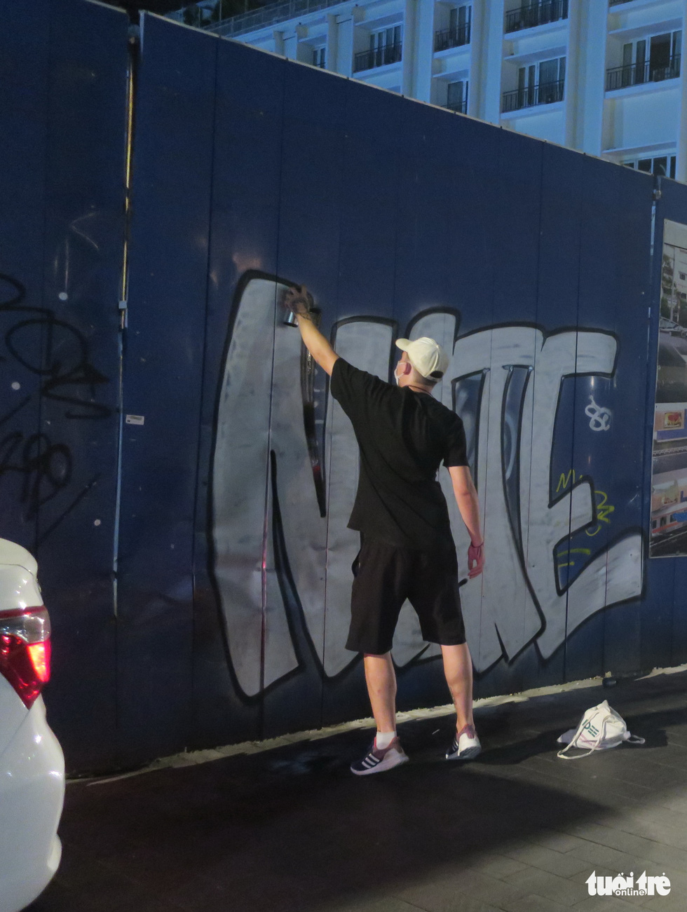 A foreign graffiti drawer spray-paints metal sheets surrounding a construction site in District 1. Graffiti drawers often operate after midnight. Photo: T.T.D. / Tuoi Tre