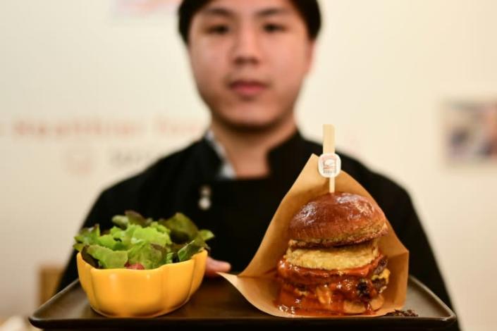 This photo taken on August 30, 2022, shows Pooripat Thiapairat, owner of 'Bounce Burger', posing with a plate of 'Cricket-burger' at his restaurant in Bangkok. Photo: AFP