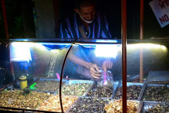 This photo taken on August 31, 2022 shows a vendor selling fried crickets and other insects along a street in Bangkok. Photo: AFP