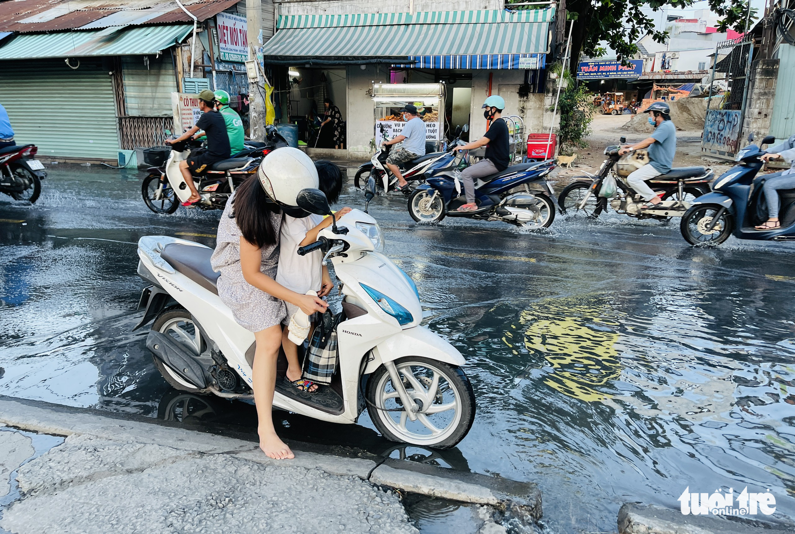 A woman takes off her shoes before traveling on a flooded street section in Ho Chi Minh City, September 13, 2022. Photo: Le Phan / Tuoi Tre
