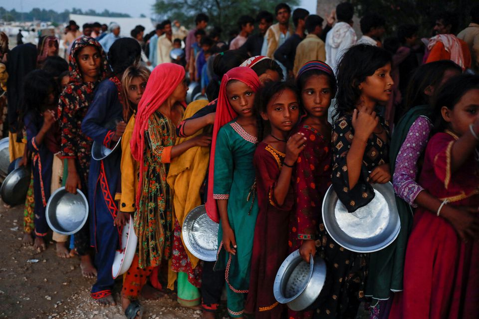 Flood victims gather to receive food handout in a camp, following rains and floods during the monsoon season in Sehwan, Pakistan September 15, 2022. Photo: Reuters