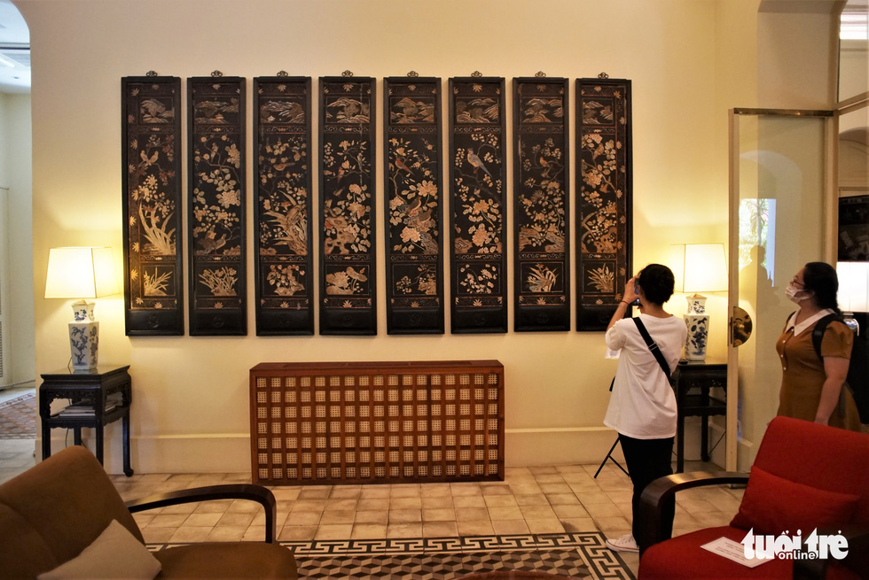 A visitor takes a picture of an eight-piece folding screen displayed on the wall of the large living room of the Consulate General of France in Ho Chi Minh City on September 17, 2022. Photo: Huynh Vy / Tuoi Tre