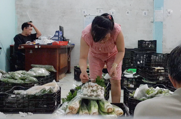 A worker sticks VietGAP labels on vegetables bought from wholesale markets. Photo: Bong Mai / Tuoi Tre
