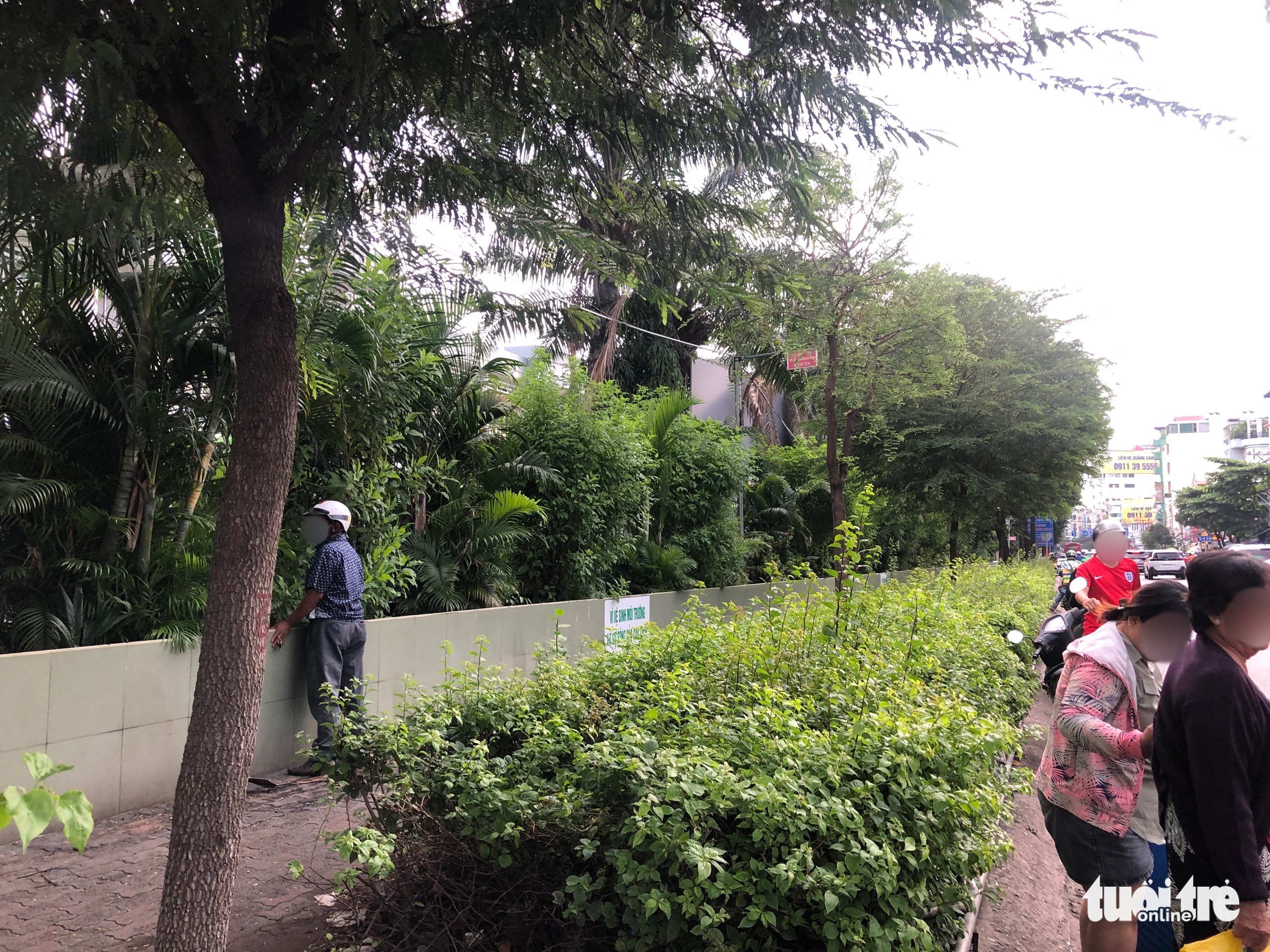 A man urinates onto a row of decorative green bushes next to a sign warning against public urination at Mien Dong Bus Station in Binh Thanh District, Ho Chi Minh City. Photo: Luu Duyen / Tuoi Tre