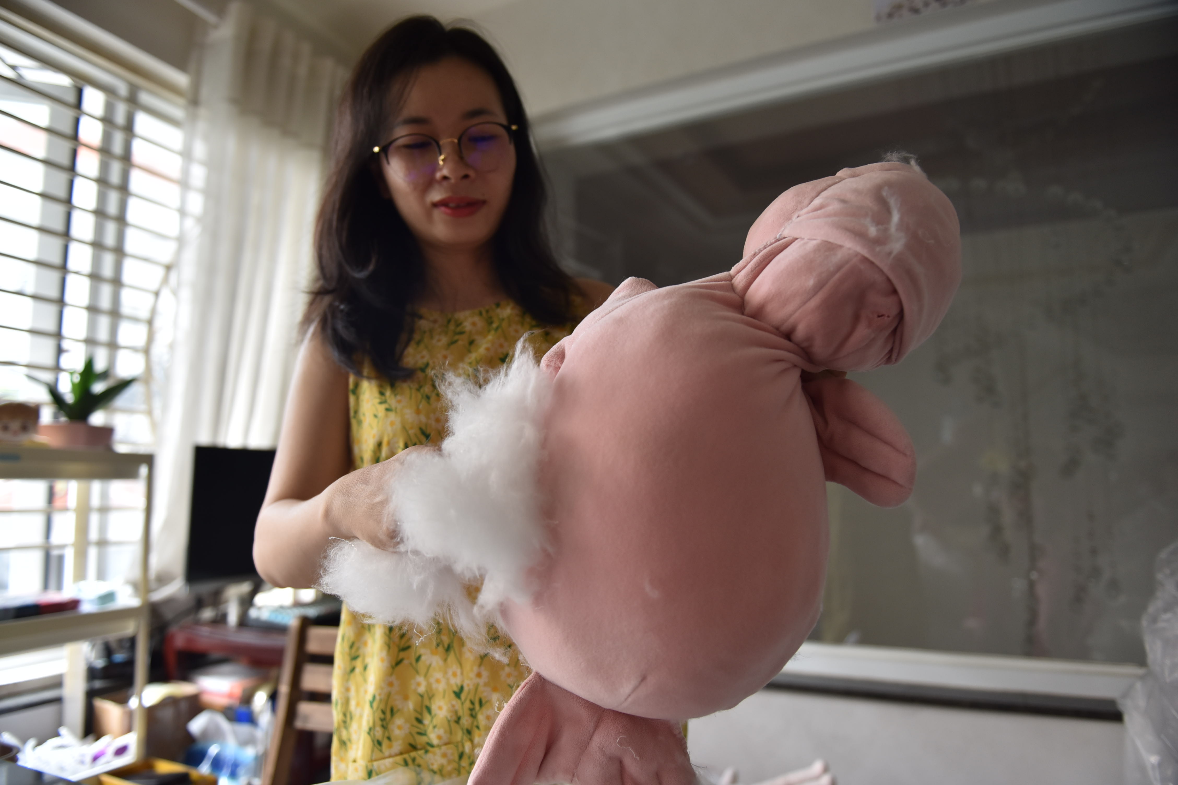 Chi fills a cuddly with new stuffing before taking a photo of it for a customer. Photo: Ngoc Phuong / Tuoi Tre News
