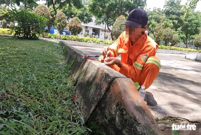 A man in the uniform of a sanitation worker prepares for his drug injection at 23/9 Park in District 1, Ho Chi Minh City, September 23, 2022. Photo: Minh Hoa / Tuoi Tre