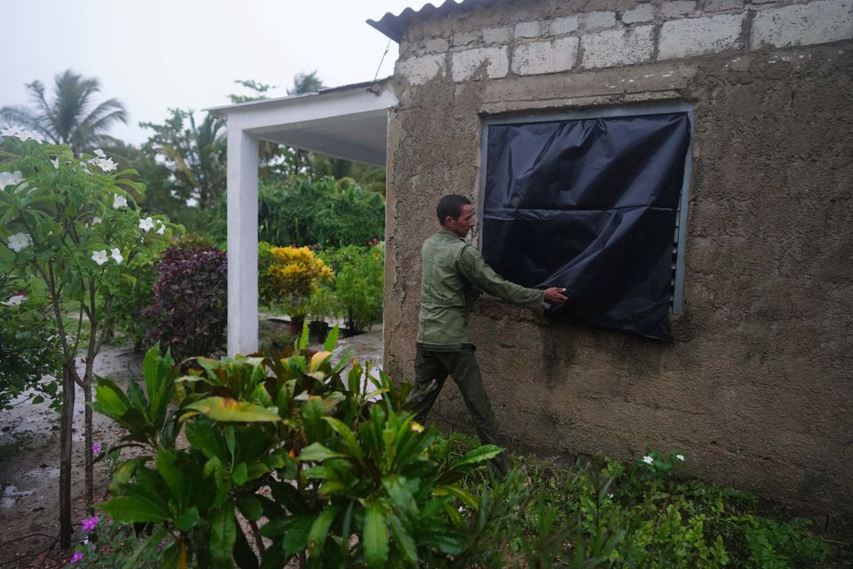 Farmer Cito Braga puts plastic on a window of his home ahead of the arrival of Hurricane Ian in Coloma, Cuba, September 26, 2022. Photo: Reuters
