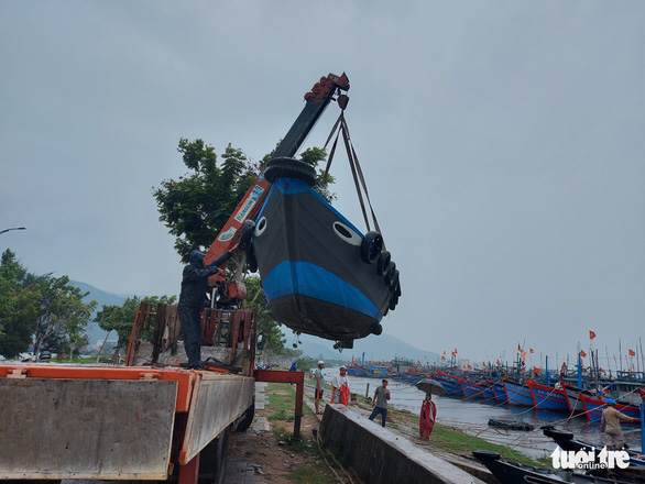 A fishing boat is seen being lifted to shore by a crane in a coastal area of central Vietnam to avoid possible damage to be caused by the coming powerful typhoon. Photo: Huu Kha / Tuoi Tre