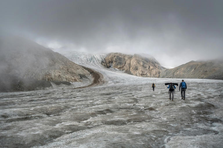 This picture taken on September 2, 2022 above Ulrichen shows glaciologist and head of 'Glacier Monitoring in Switzerland' (GLAMOS) network Matthias Huss (with yellow shirt) during a visit with his team on the Gries glacier to takes readings of measuring equipment. Photo: AFP