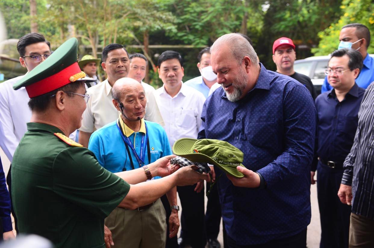 Colonel Nguyen Tuan Bao (L), deputy political commissar of the Ho Chi Minh City Command, presents a broad-brimmed cap and a Vietnamese  traditional checkered black and white shawl to Prime Minister Manuel Marrero Cruz at the Cu Chi Tunnels in Cu Chi District, Ho Chi Minh City, October 1, 2022. Photo: Quang Dinh / Tuoi Tre