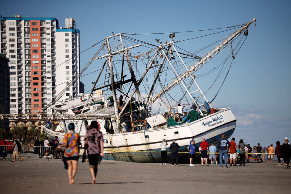 Beachgoers look at a large shrimping boat that was swept ashore by hurricane Ian in Myrtle Beach, South Carolina, U.S., October 1, 2022. Photo: Reuters