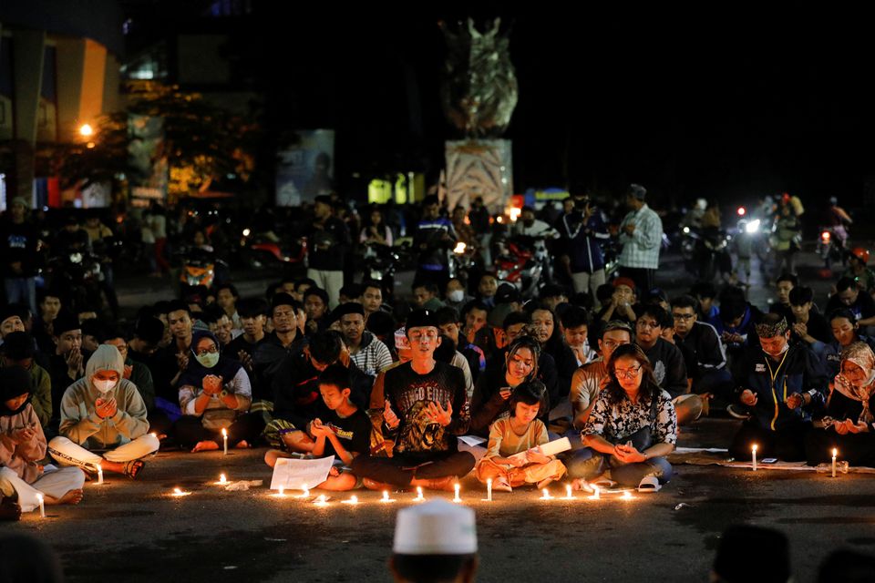 Arema football club supporters pray during a vigil outside the Kanjuruhan stadium to pay condolence to the victims, after a riot and stampede following soccer match between Arema vs Persebaya outside in Malang, East Java province, Indonesia, October 2, 2022. Photo: Reuters